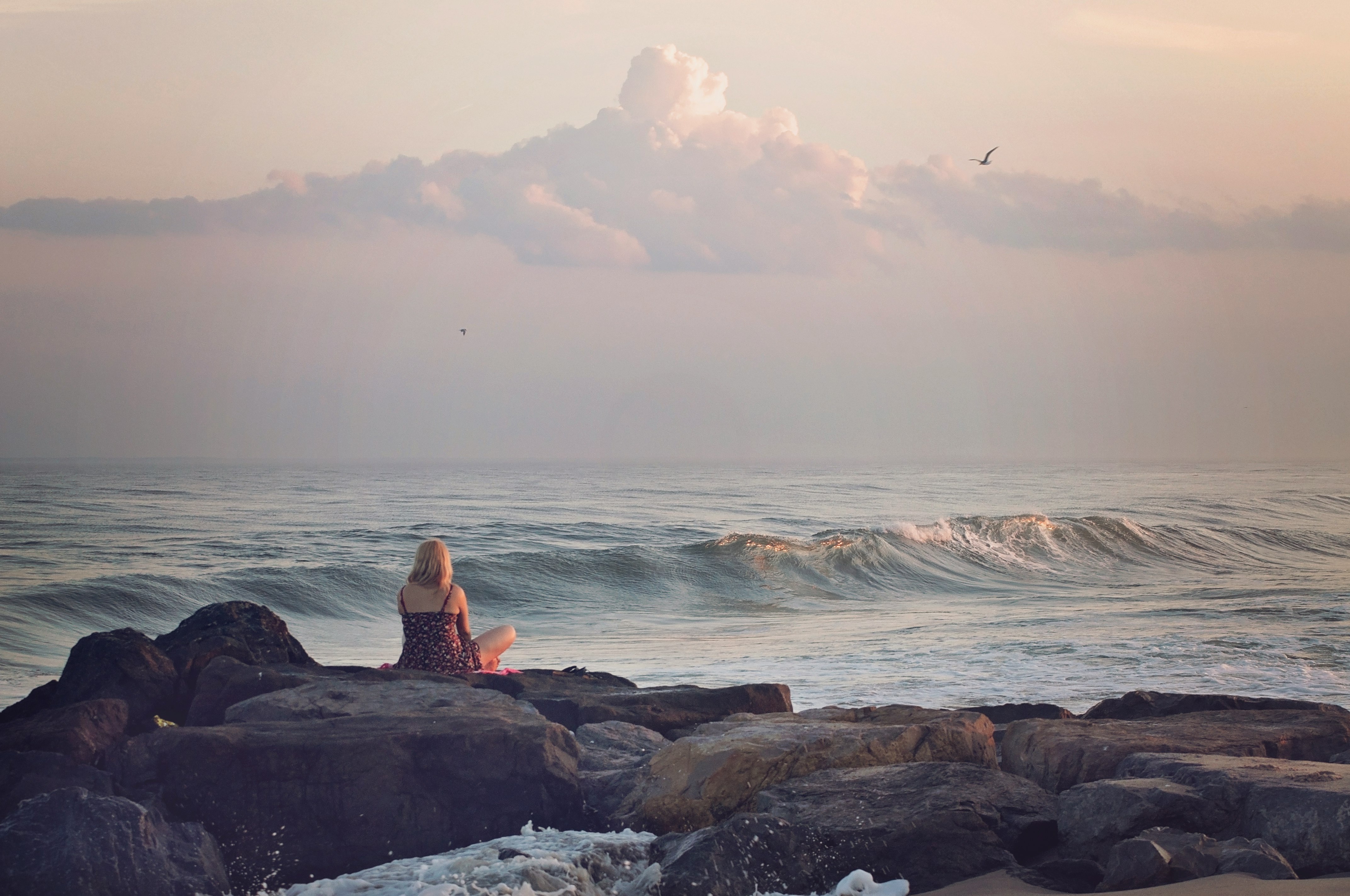 woman sitting on rock near body of water during daytime